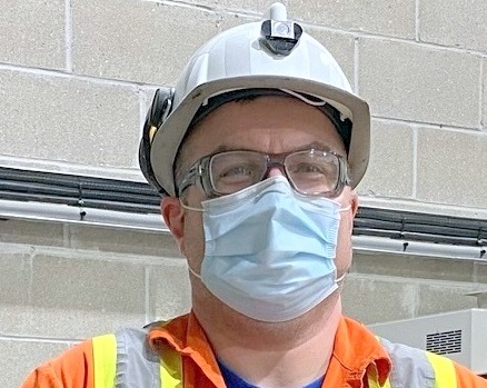 Man wearing hardhat, glasses, and mask