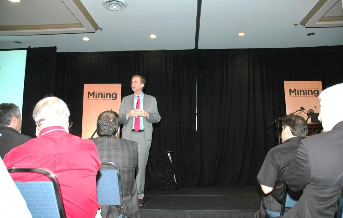 Dr. Peter Strahlendorf onstage presenting to conference audience on the Internal Responsibility System
