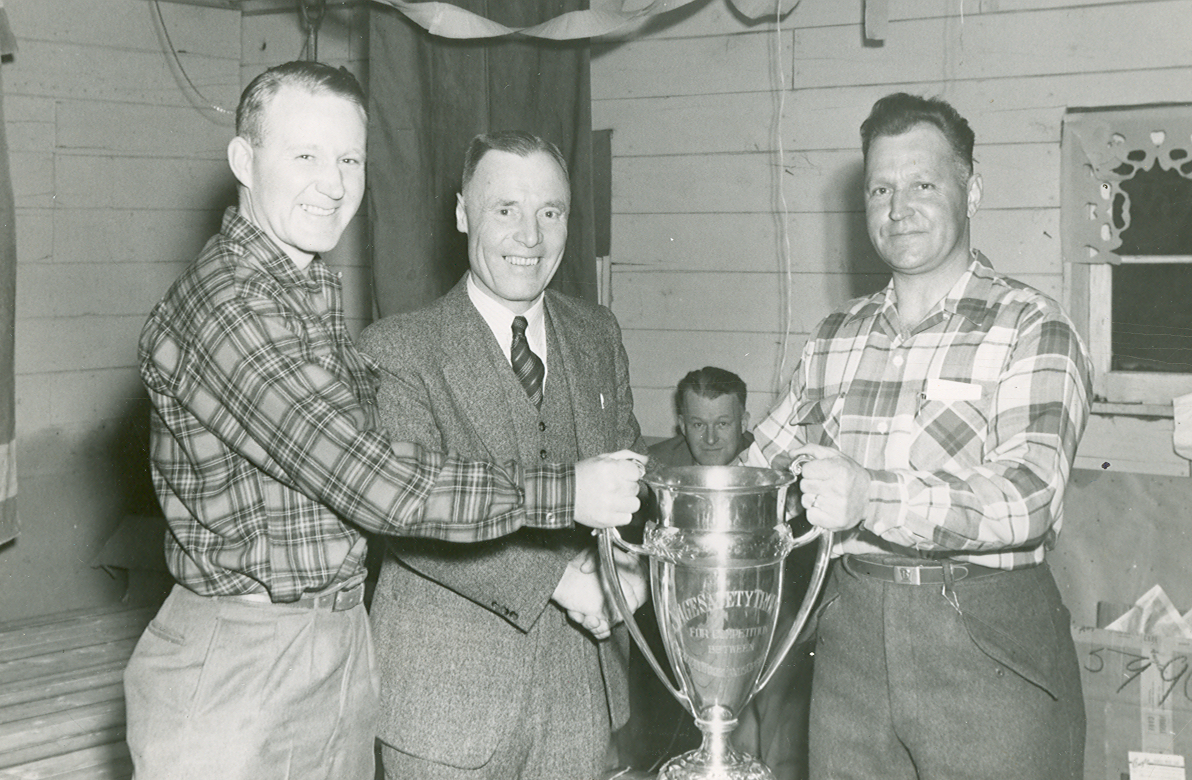 Archival photo of three workers accepting workplace safety trophy