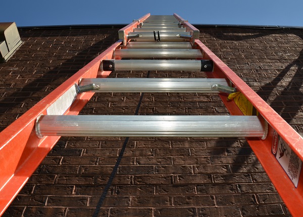 View looking up a ladder placed against a brick wall