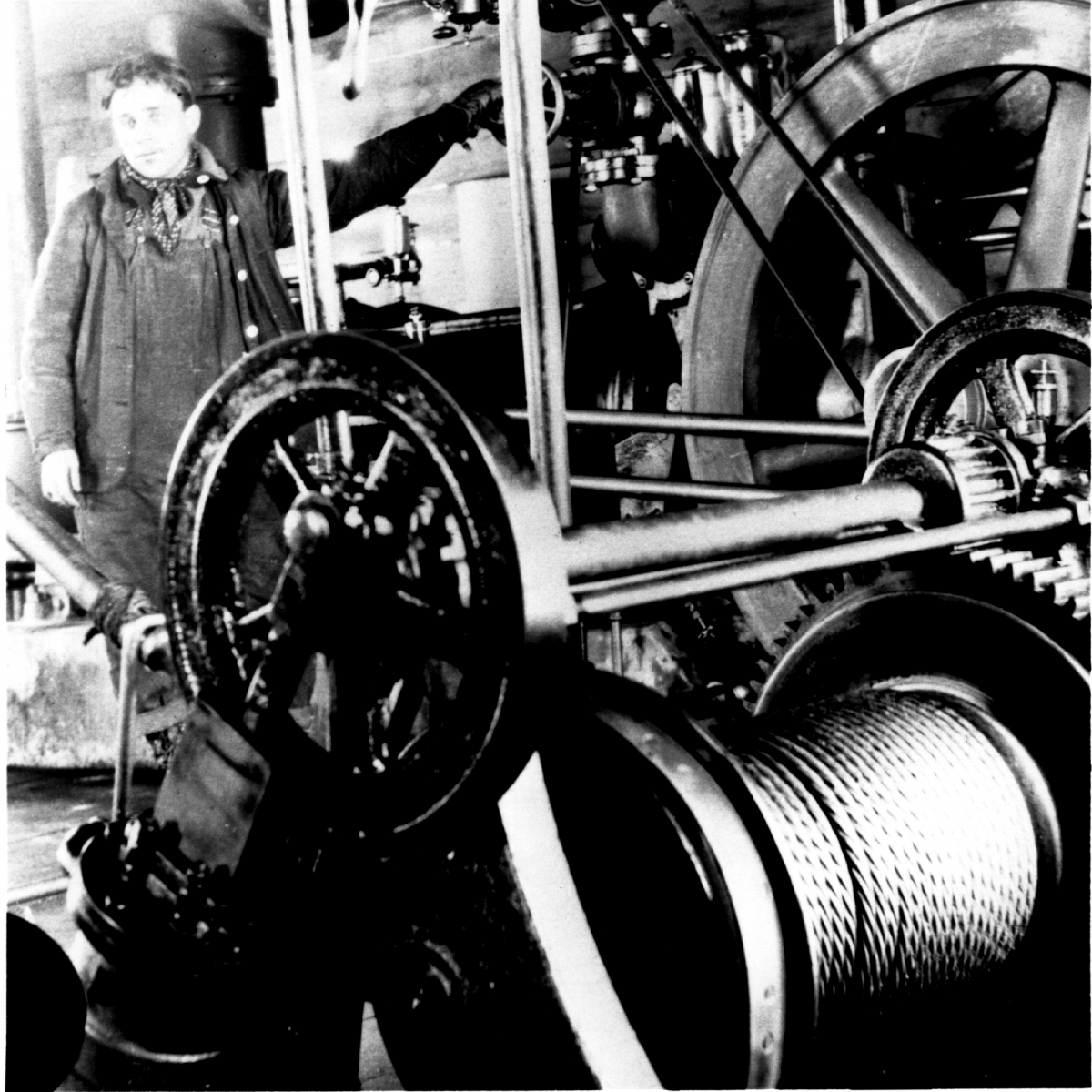 Archival photo of worker standing by industrial machine