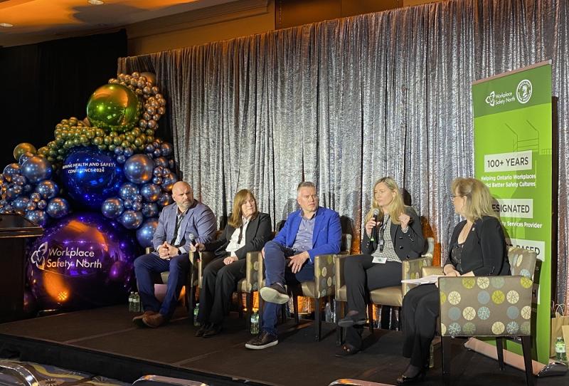 Group of five people sitting onstage at conference panel