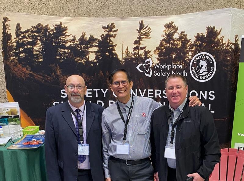 Three men standing in front of trade show booth