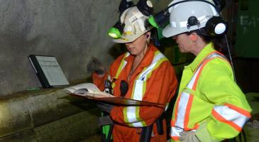 Two underground mine workers reviewing paperwork