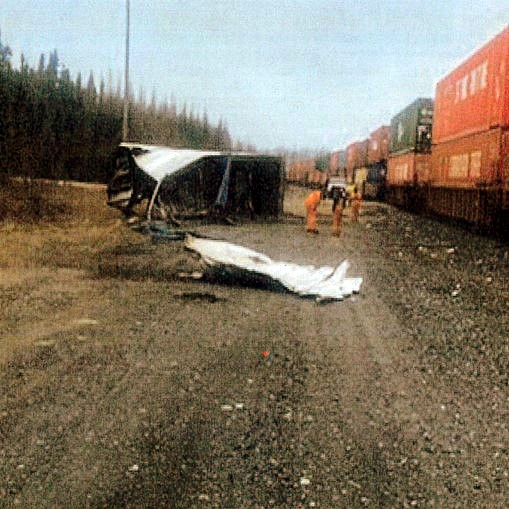 Mangled truck trailer lying in its side next to freight train